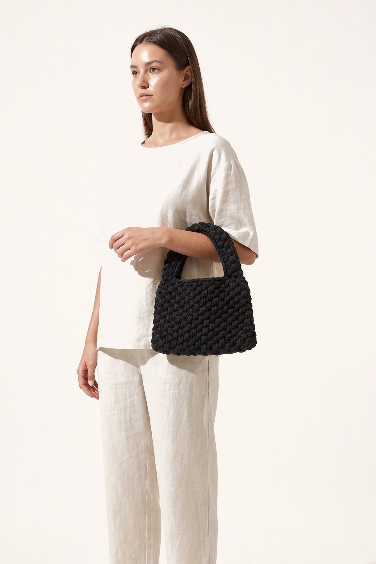 Model in a linen outfit carrying the Wren black crochet tote bag.