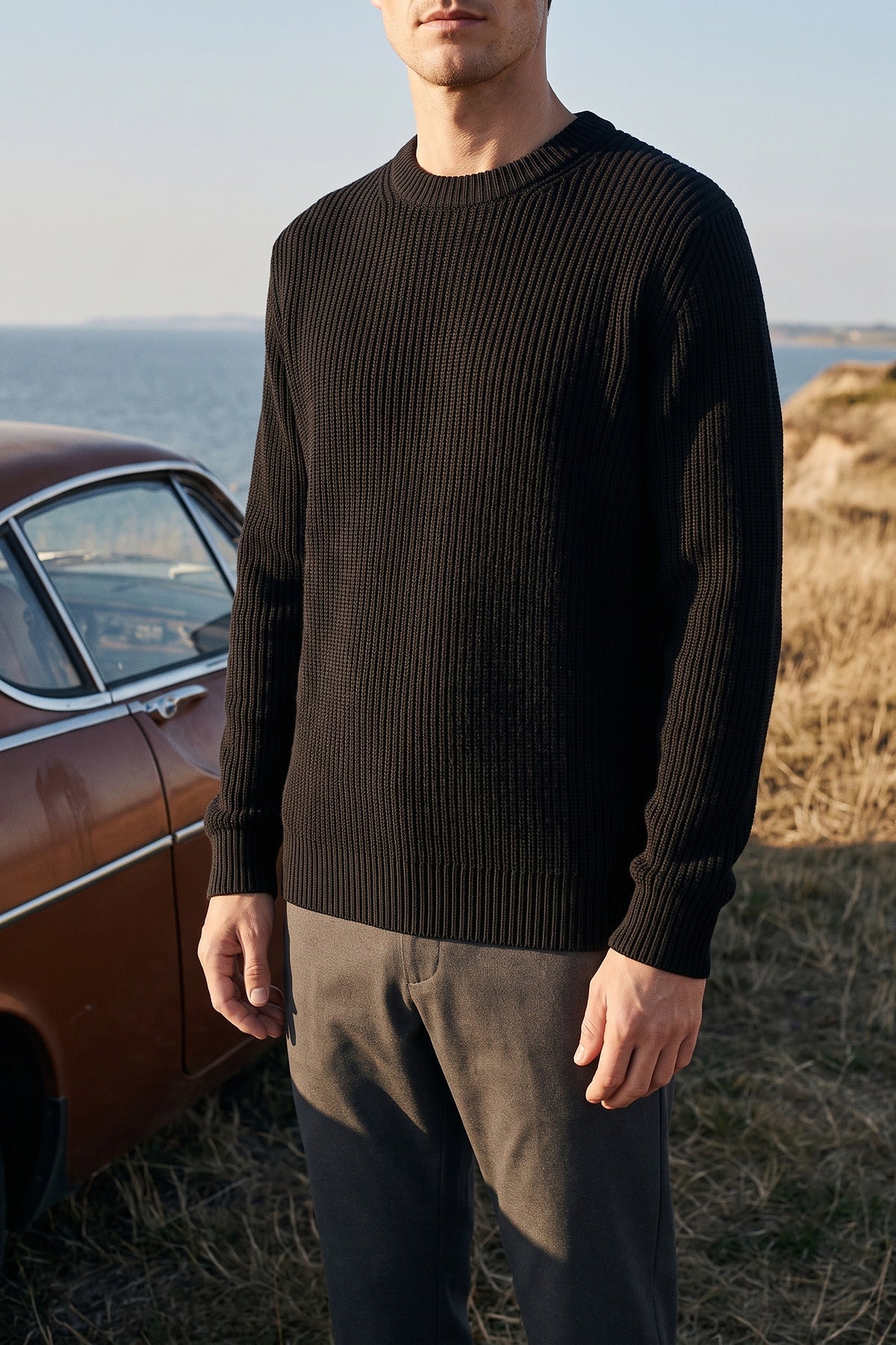 Man in a dark ribbed crew-neck jumper on a coastal path.