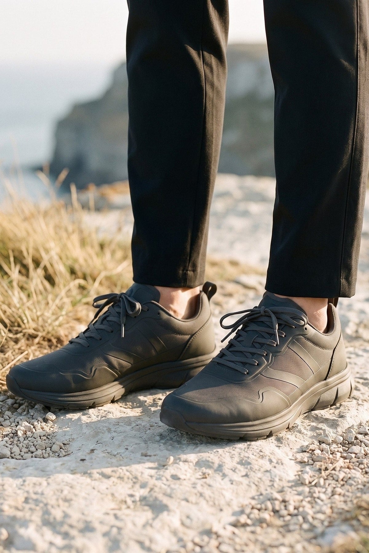 Dark trainers and cropped trousers on a chalk path by the coast.